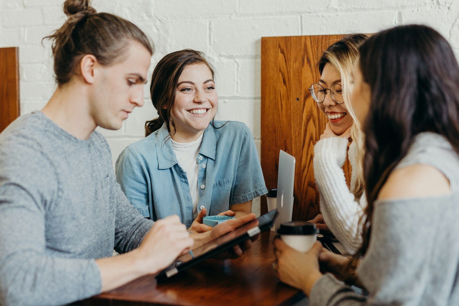 Four students working together around a phone and laptop
